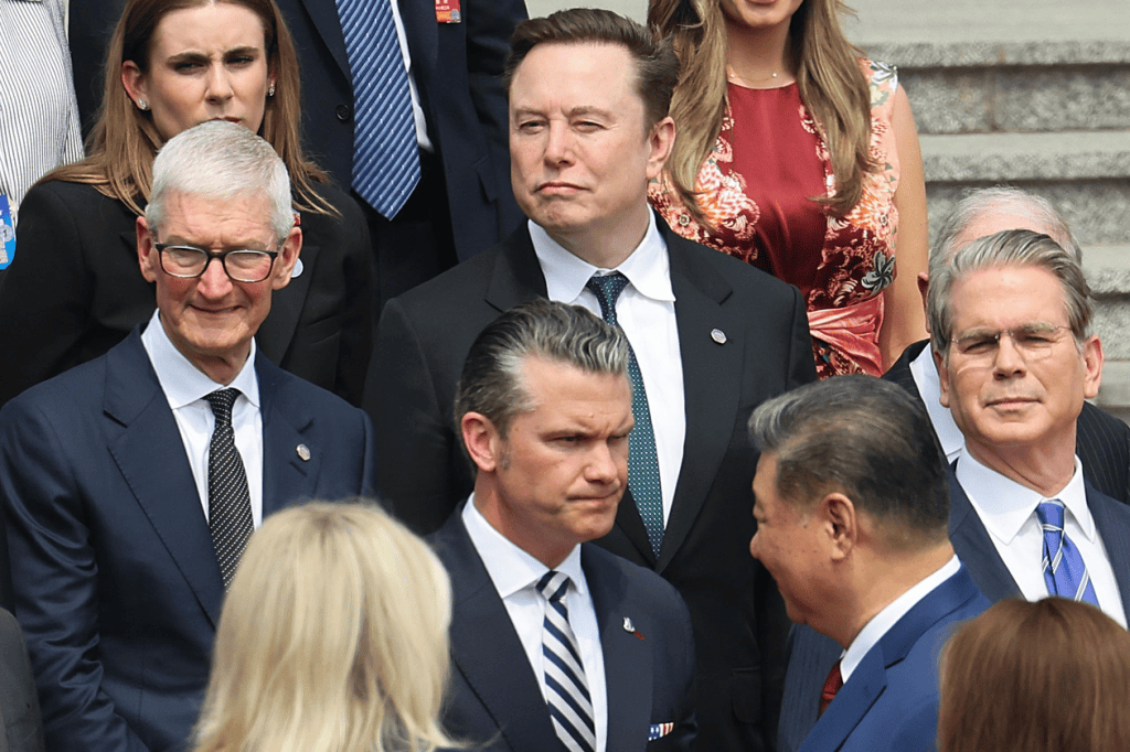 A group of prominent individuals, including business leaders and politicians, gathered outdoors for a photo opportunity, with a focus on their expressions and interactions.